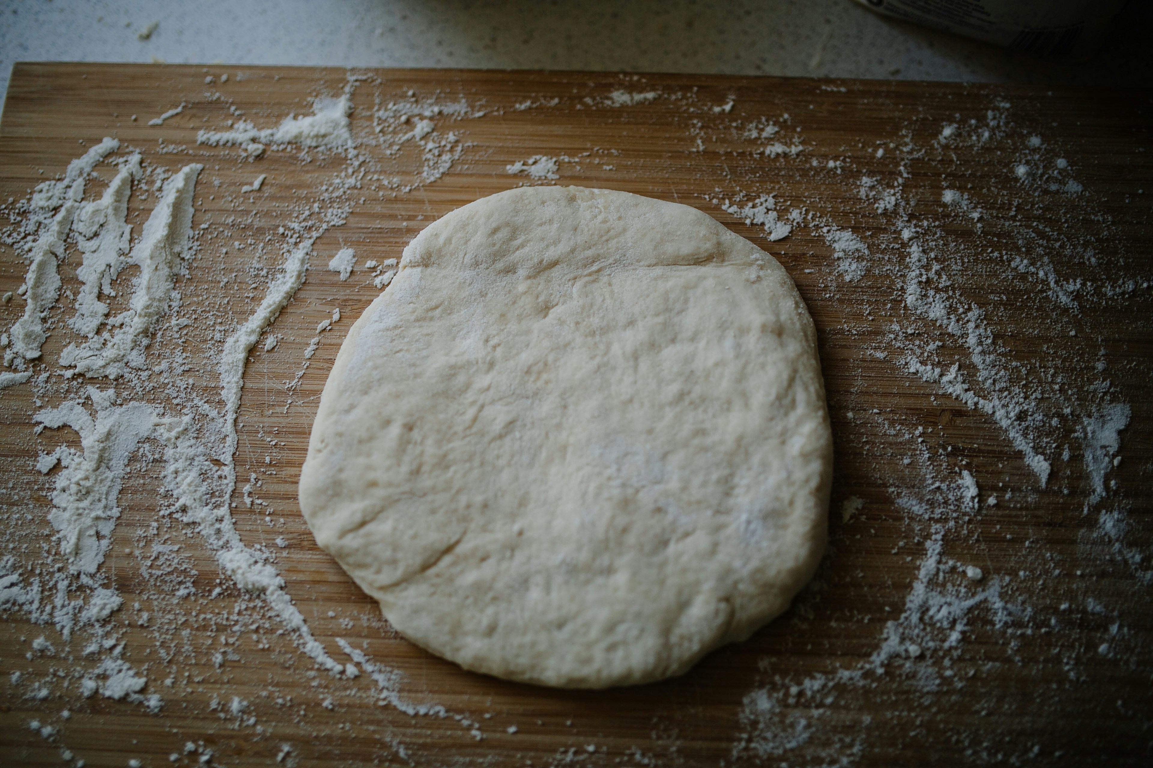 Pâte à pizza et farine sur planche en bois